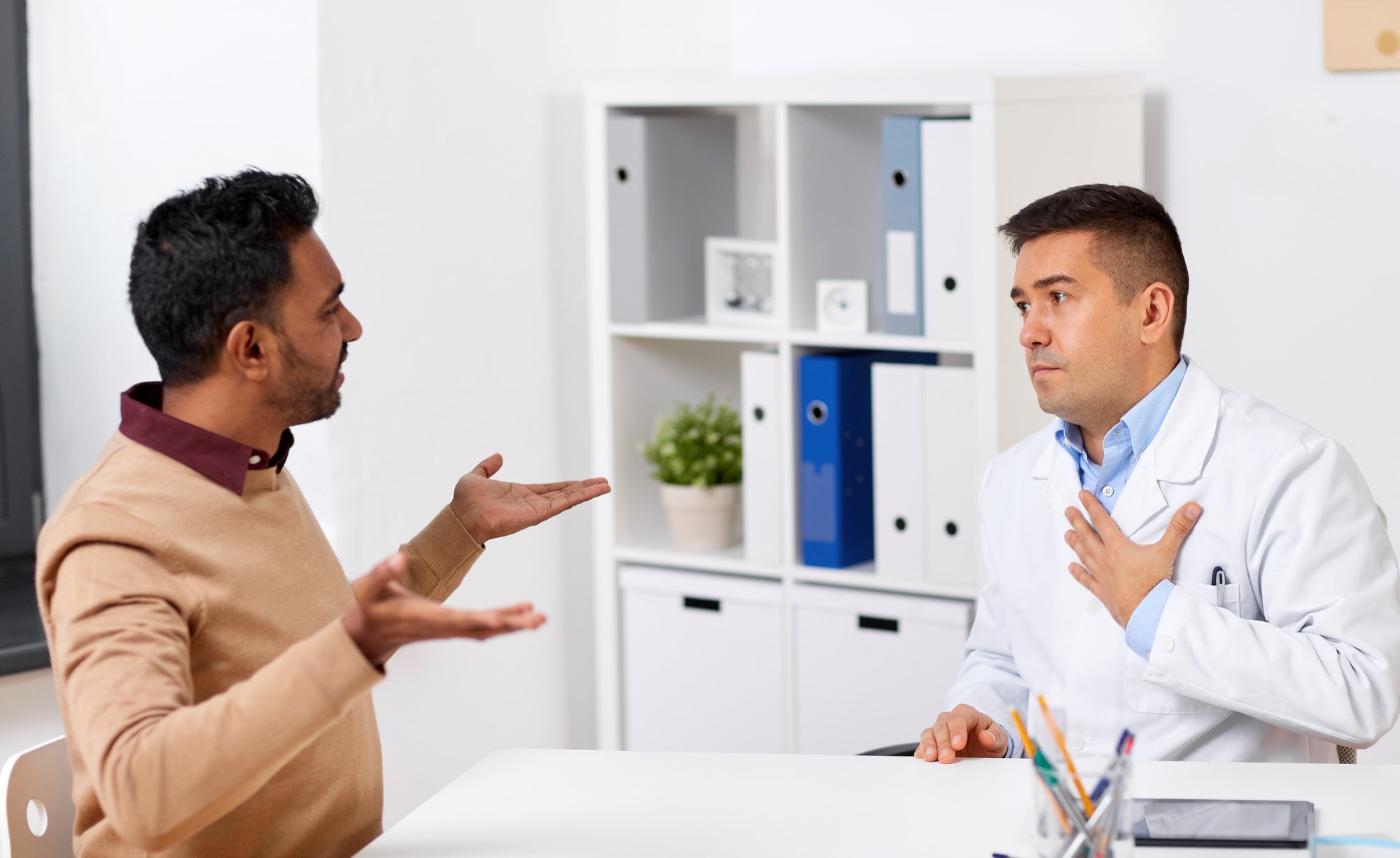 Healthcare professional meeting privately with an individual to discuss a misconduct concern in a medical office. Healthcare professional meeting privately with an individual to discuss a misconduct concern in a medical office.